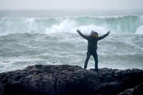 A tourists poses for a photograph on the Burren, near Black Head lighthouse, County Clare in the Republic of Ireland as Storm Jocelyn hits.