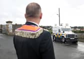 An Orangeman watches a PSNI Land Rovers head towards the Garvaghy Road where protestors (inset top) had blocked the road