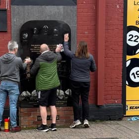 SDLP Councillor Gary McKeown helps local residents clean paint off the memorial to five people murdered by the UDA in the Sean Graham Bookmakers attack.