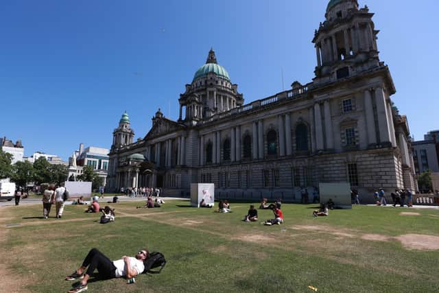 People relax in the sun on the lawn of Belfast City Hall. Picture date: Wednesday June 14, 2023.