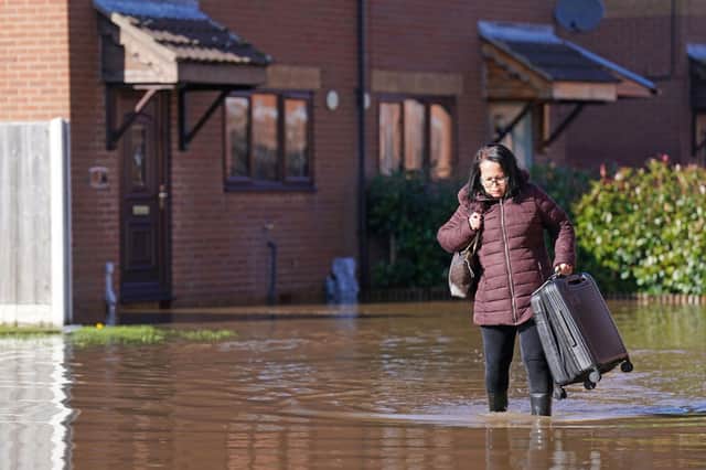 A woman with a suitcase walks through flood water in Retford in Nottinghamshire, after Storm Babet battered the UK, causing widespread flooding and high winds