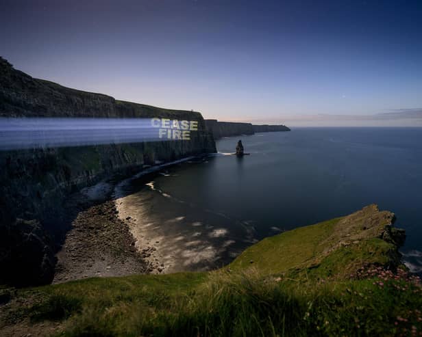 A projector beaming the words 'cease fire' onto the Cliffs of Moher (George Karbus) in relation to Gaza