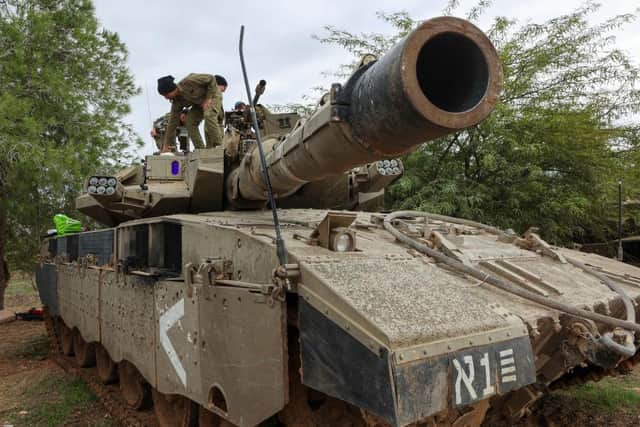 Israeli troops carrry out maintenance on tanks deployed on the southern border with the Gaza Strip