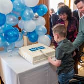 Transplant waiting list patient Daithi Mac Gabhann cuts the NHS anniversary cake at Stormont