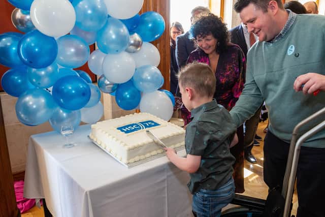Transplant waiting list patient Daithi Mac Gabhann cuts the NHS anniversary cake at Stormont