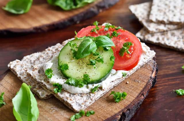 A rye crisp bread snack with humus, tomato and cucumber.