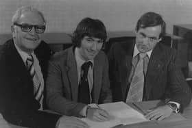 Honda Racing team manager Barry Symmons (right) watches on as Joey Dunlop signs his first Honda contract in 1981. Also pictured is Joey's former sponsor, John Rea. Picture: News Letter Archives