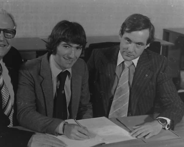 Honda Racing team manager Barry Symmons (right) watches on as Joey Dunlop signs his first Honda contract in 1981. Also pictured is Joey's former sponsor, John Rea. Picture: News Letter Archives