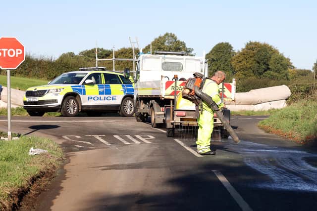 Police look on as workers try to clean oil from a section of the Mid-Antrim 150 road race circuit at Clough, Co. Antrim after the track was sabotaged in the early hours of the morning.