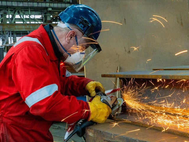 A shipyard worker at Harland & Wolff welding materials in the fabrication hall
