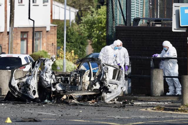 Forensic teams carry out checks after a car bomb exploded outside Dunmurry Police station on Saturday night.