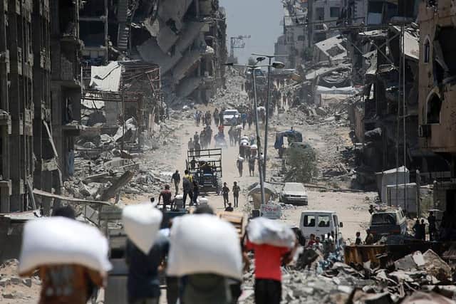 Palestinians carry bags of flour that they obtained from aid trucks which entered Gaza through the Zikim crossing point, in Jabalia in the northern Gaza Strip on August 1, 2025. The UN human rights office said on August 1 that 1,373 Palestinians have been killed while waiting for aid in the shortage-stricken Gaza Strip since late May, most of them by the Israeli military. (Photo by Bashar TALEB / AFP via Getty Images