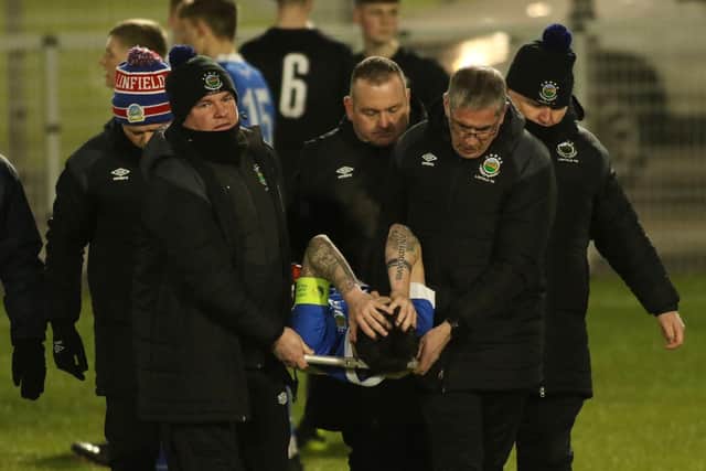 Corai Quinn is stretchered off after breaking his leg in February. PIC: Linfield FC