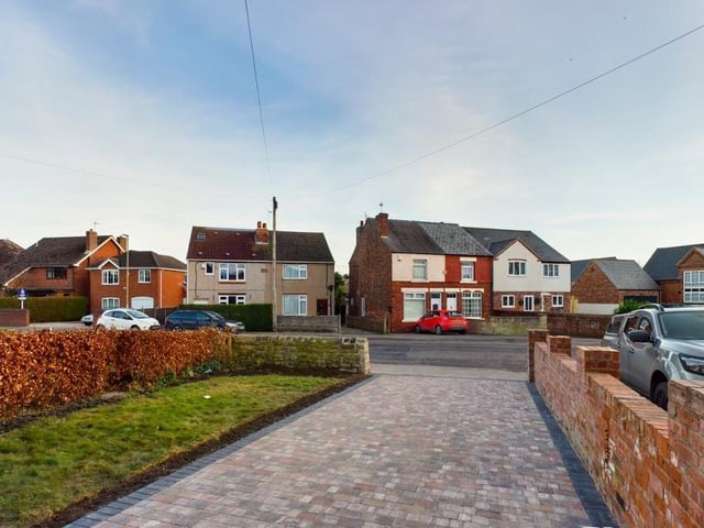 At the front of the £250,000 property, this spacious driveway provides plenty of space for off-street parking. Either side of the drive are a lawned garden with a hedged border, and a dry stone boundary wall.