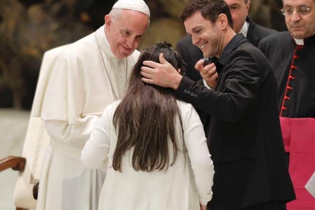 Pope Francis greets an ill girl accompanied by Argentine singer Axel, right, during an audience with Huntington's disease families, in the Paul VI Hall, at the Vatican, Thursday, May 18, 2017