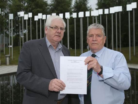 Michael Gallagher (left) who lost his son Aiden, and Stanley McComb (right), who lost his wife Ann in the Omagh bombing hold a writ in the Omagh Memorial Garden.