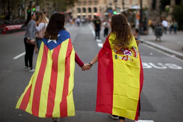 Irene Guszman, 15, wearing a Spanish flag on her shoulders and Mariona Esteve, 14, with an 'estelada' or independence flag, walk along the street to take part on a demonstration in Barcelona, Spain, Tuesday Oct.3, 2017. Thousands of people demonstrated against the confiscation of ballot boxes and charges on unarmed civilians during Sunday's referendum on Catalonia's secession from Spain that was previously declared illegal by Spain's Constitutional Court