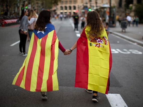 Irene Guszman, 15, wearing a Spanish flag on her shoulders and Mariona Esteve, 14, with an 'estelada' or independence flag, walk along the street to take part on a demonstration in Barcelona, Spain, Tuesday Oct.3, 2017. Thousands of people demonstrated against the confiscation of ballot boxes and charges on unarmed civilians during Sunday's referendum on Catalonia's secession from Spain that was previously declared illegal by Spain's Constitutional Court