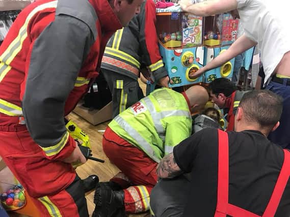 Nottinghamshire Fire & Rescue Service handout photo of firefighters carefully dismantling a toy vending machine, in order to free a three-year-old girl, after she got both hands trapped in the mechanism the Matalan store in Chilwell, Nottingham, on Monday