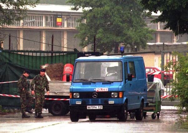 British soldiers walk to a police van that partly hides a pickup truck in front of a side entrance to the Osnabrueck British army barracks after an IRA mortar attack in June 1996.