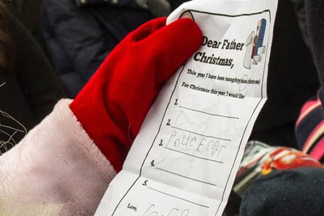 The Duke of Cambridge hands Prince George's Christmas Wish List to a man dressed as Santa Claus as he visits Esplanade Park's Christmas market in Helsinki