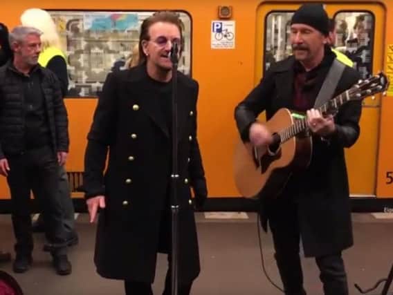 Bono and the Edge perform in an underground station in Berlin.