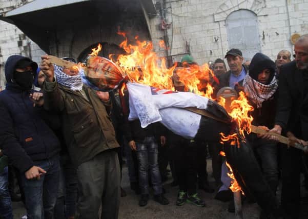 Palestinian protesters burn an effigy of U.S. President Donald Trump, during a protest against the U.S. decision to recognize Jerusalem as Israel's capital, in the West Bank City of Nablus, Thursday, Dec. 7, 2017. (AP Photo/Majdi Mohammed)