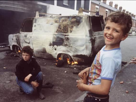 Burning vehicles on the Falls Road provide a playground for children