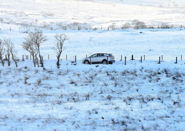 A white vehicle makes its way along a snowy lane amid a bright and icy landscape on Divis Mountain yesterday