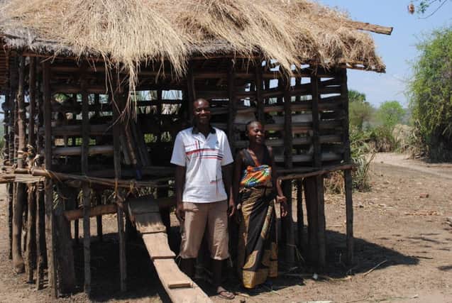 Samuel Fred with his wife and the house where he keeps his goats in the village of Fombe