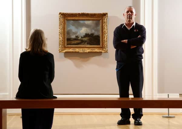 A security guard keeps watch as the three times stolen painting by Dutch master Jacob van Ruisdal was unveiled yesterday in the Ulster Museum