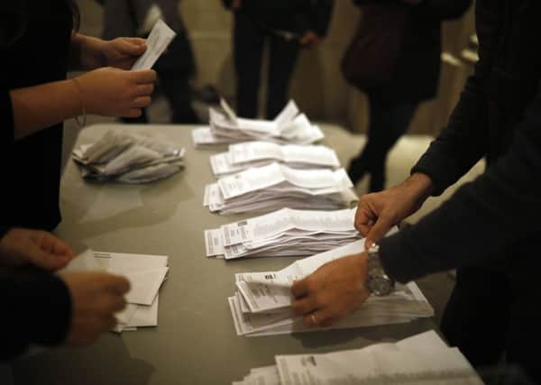 Polling station workers start to count votes for the Catalan regional election in Barcelona, Spain, on Thursday, Dec. 21, 2017. Separatists won a majority of the seats but not of the votes. (AP Photo/Santi Palacios)