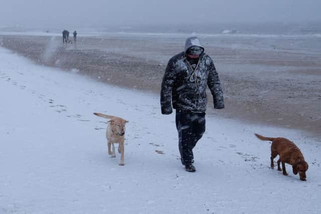 A dog walker leaves footprints in the snow on Whitley Bay beach on Sunday,after the UK froze on the coldest night in nearly two years. Photo credit should read: Owen Humphreys/PA Wire