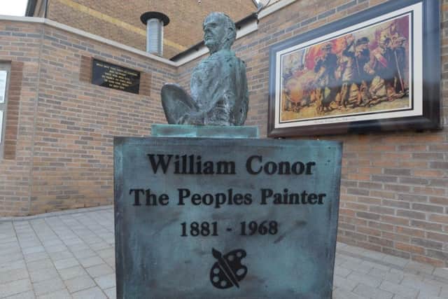 A bronze statue of William Conor stands at the corner of Northumberland Street and the Shankill Road in Belfast