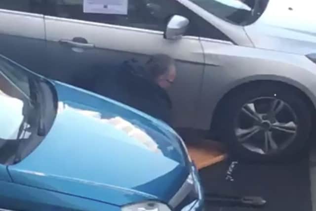 A still image from a video apparently showing Sinn Feins Gerry Kelly cutting a wheel clamp from his car with bolt cutters near Belfast city centre