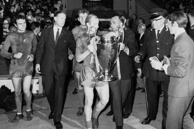 Manchester United's Bobby Charlton examines the European Cup, watched by teammates John Aston (left) and Alex Stepney (behind Charlton).