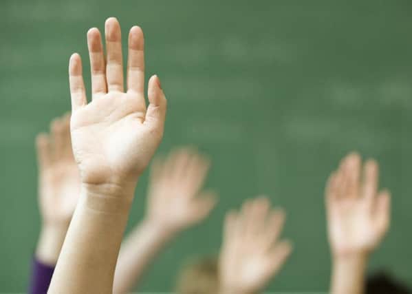 Pupils raise hands in a classroom. Stock image.