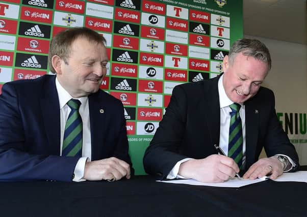 Northern Ireland manager Michael ONeill puts pen to paper on the four-year contract extension, watched by president of the Irish FA David Martin