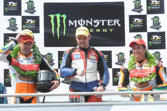 Michael Dunlop celebrates victory in the second Supersport race at the 2013 Isle of Man TT with runner-up Bruce Anstey and Iohn McGuinness.