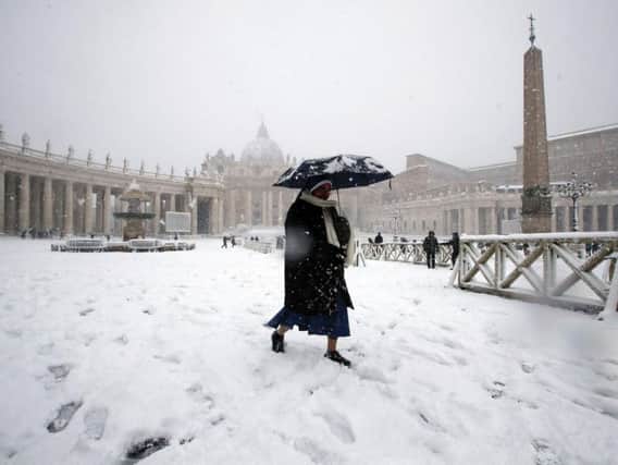 A nun walks under a snowfall in St. Peter's Square at the Vatican Monday, Feb. 26, 2018.