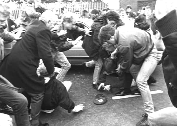 Corporal Derek Woods emerges from his car with his gun in hand and is quickly beaten to the ground by the mob at the IRA funeral of Kevin Brady in March 1988