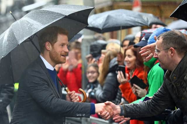 Prince Harry shelters under an umbrella as he meets wellwishers during a walkabout in Belfast after he and Meghan Markle visited the Crown Bar in the city centre. Photo: Gareth Fuller/PA Wire