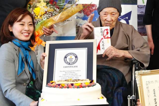 Masazou Nonaka, right, receives the certificate from Guinness World Records as the world's oldest living man at age 112 years and 259 days during a ceremony in Ashoro on Japan's northern main island of Hokkaido