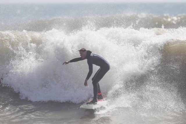 A surfer rides a wave off of Boscombe Beach, Dorset.