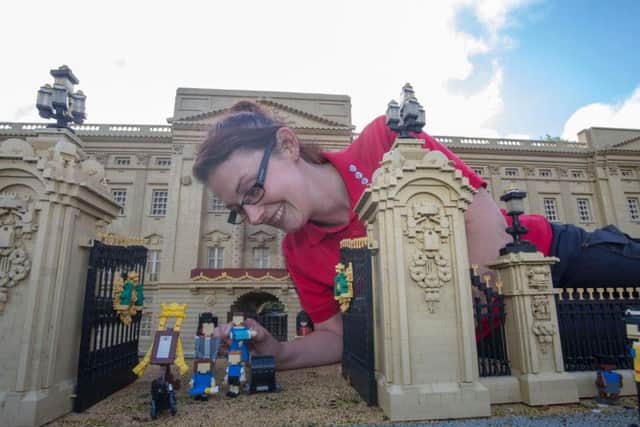 Model maker Kat James puts the finishing touches to Lego figures of the Duke and Duchess of Cambridge and their family outside the Buckingham Palace model at LEGOLAND Windsor Resort in Berkshire, which has welcomed the latest Royal baby to its Miniland attraction.
