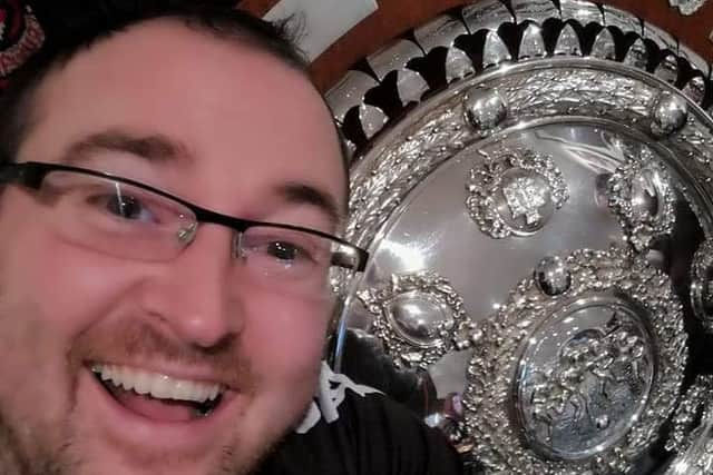 Crusaders fan James Branagh pictured with the Co Antrim Shield, which the club won earlier this season