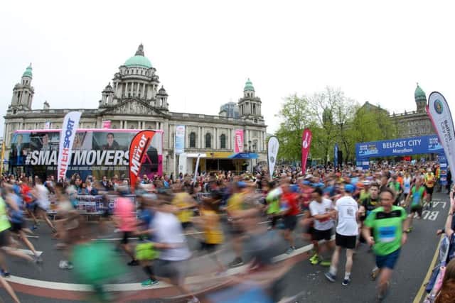 A blur of runners shoot past Belfast City Hall at the start of the 2018 race