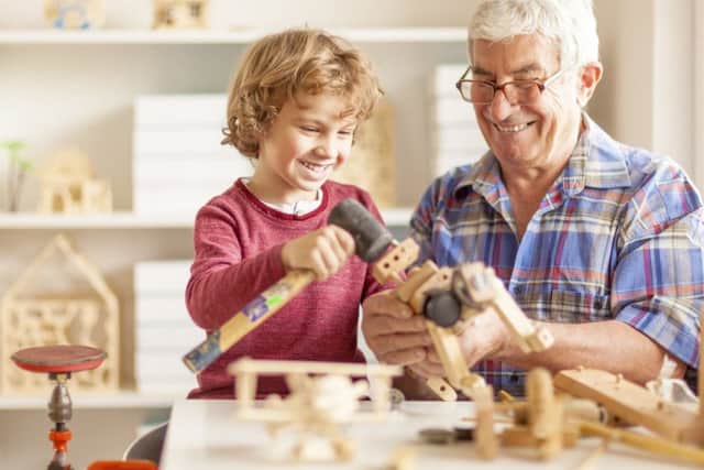 Grandpa and his grandson crafting wooden toys together in a workshop