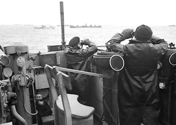 Officers on the bridge of a destroyer, escorting a large convoy of ships, keep a sharp look out for attacking enemy submarines