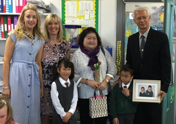 P3 pupils Lydia Briggs and Theo Souch present a picture to Thai adoption officials Miss Chintana Watcharakul and Mr Suthi Jantarawong during their visit to Dromore Central Primary School. Also pictured are teachers Miss McKeown and Mrs Mackay.